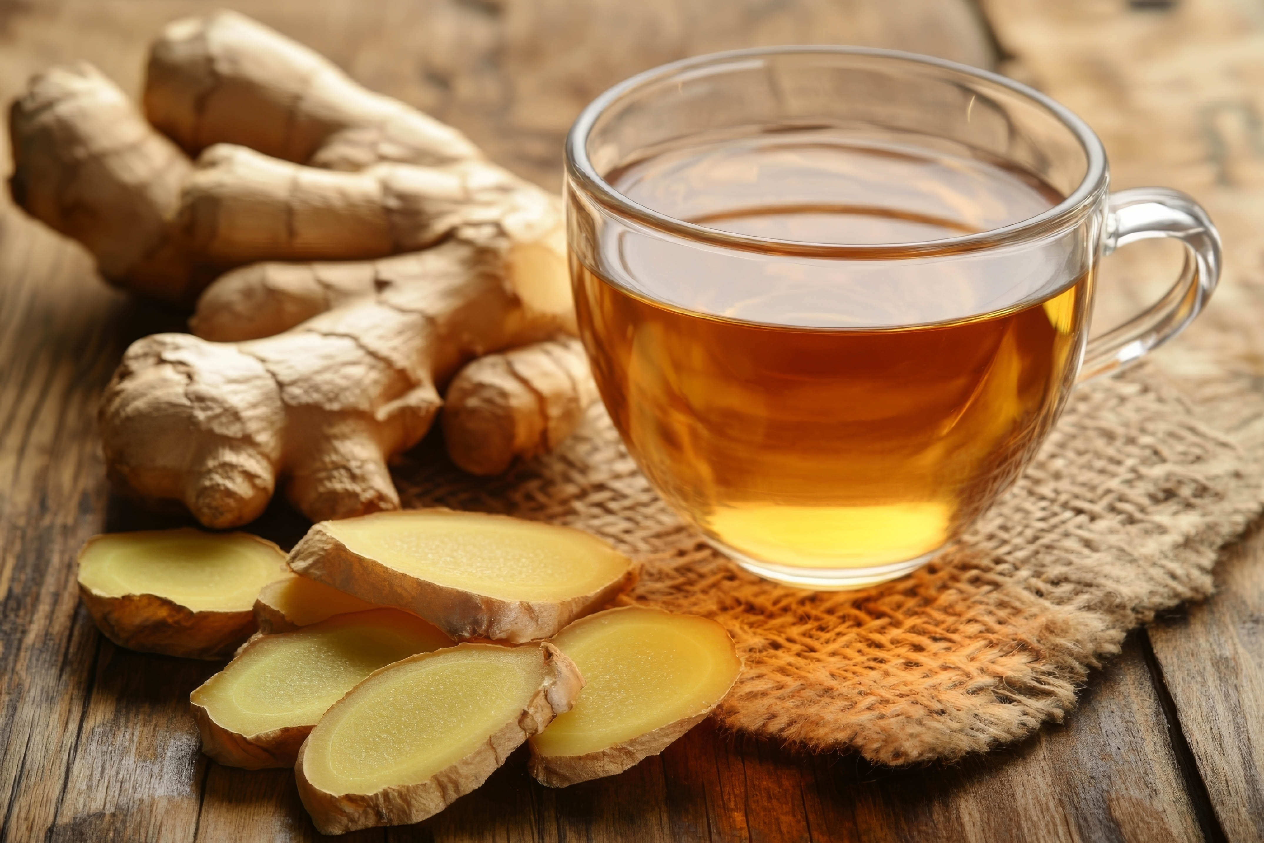 Brewed ginger tea and ginger root surrounding the glass cup Brewed ginger tea and ginger root surrounding the glass cup